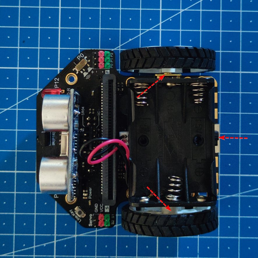 Imagen del robot Maqueen totalmente montado. Aparecen tres flechas rojas que indican cómo debe quedar el portapilas. 
