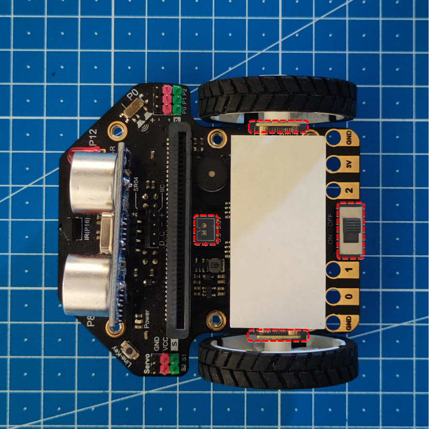 Imagen del robot con el sensor, las ruedas y el material adhesivo colocado sobre los motores. Mediante unos rectángulos rojos se indica las zonas que deben quedan libres.